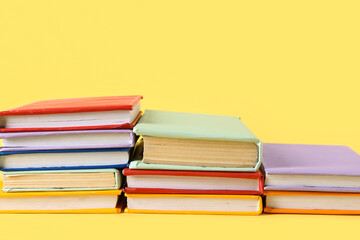 Stacks of colorful books on yellow background