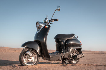 Black retro scooter in the Namib Desert at sunset — a bold mix of style, freedom, and timeless adventure. Perfect for travel, lifestyle, and vintage-themed campaigns.

