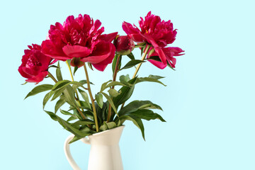 Jug with beautiful peony flowers on blue background