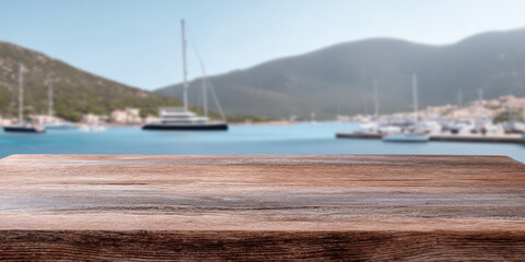 A coastal wooden table foreground with a blurred view of mountains and boats in the background, creating a serene and inviting atmosphere