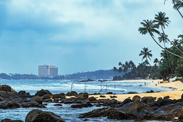  peaceful morning on a tropical Sri Lankan beach, with soft pink hues, palm trees and waves gently lapping at the shore