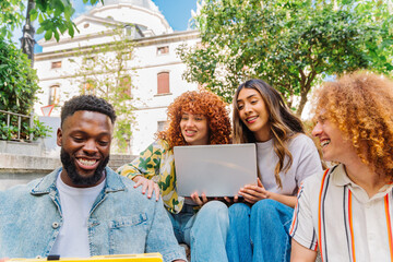 Diverse college students working together on laptop, smiling and collaborating while sitting on university steps during sunny day