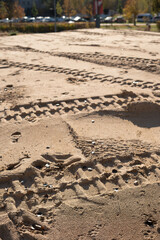 photo Sandy Landscape with Tire and Foot Impressions Creating Intricate Patterns in Nature's Canvas Under a Clear Sky on a Sunlit Day in a Serene Outdoor Environment