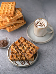 photo Delicious homemade waffles with rich chocolate sauce and frothy cappuccino creating a perfect combination for a satisfying breakfast or delightful brunch experience