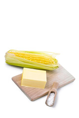 Fresh corn with butter and salt on a wooden board on a white background