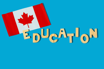 Canadian flag and the word Education from wooden letters on a blue background.