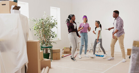A crazy happy family paints the walls with white paint using brushes. They dance and sing in the middle of the room while the parents play with their children, preparing the house for renovation.