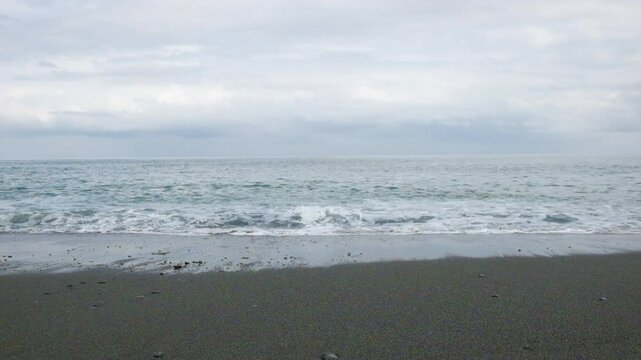 白い雲と青空と穏やかな水平線から打ち寄せ波打ち際で割れる白い波_hs_24fps
