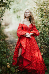 girl in a lush red dress on a summer day in nature in the garden