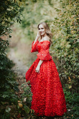 girl in a lush red dress on a summer day in nature in the garden