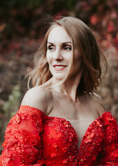 girl in a lush red dress on a summer day in nature in the garden