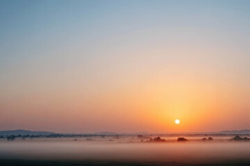 breathtaking sunrise over scenic hill enveloped in soft fog