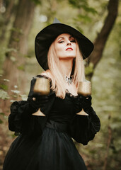 girl in a fluffy black dress and hat, halloween in the forest, magic with glasses