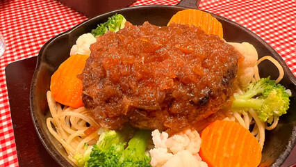 Japanese Hamburg Steak with Onion Sauce Served Hot on Skillet with Vegetables and Pasta – Comfort Food from a Traditional Japanese Restaurant