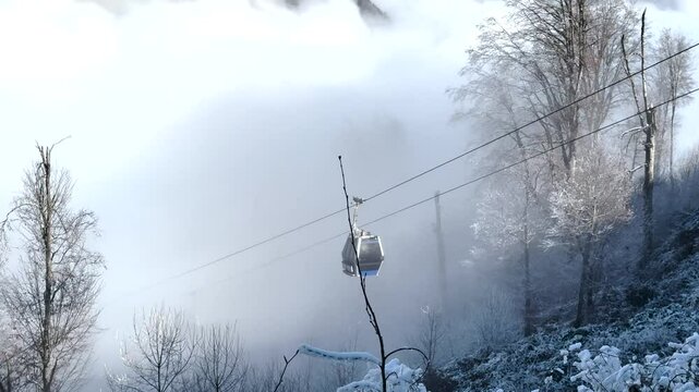 Chair lift moves through misty, snow-covered forest in the mountains of Gebele. Gebele, Azerbaijan
