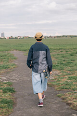 Teenager girl walking away carrying skateboard in a park