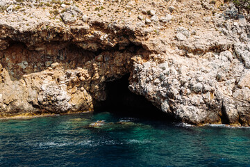 Sea cave in a rocky shore with turquoise transparent water. Picturesque natural landscape with...