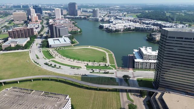 Elevated railway with scenic view of Lake Carolyn in downtown Las Colinas, mixed-use development major urban center in Irving, Texas, high-rise glass office buildings, lakeside apartment units