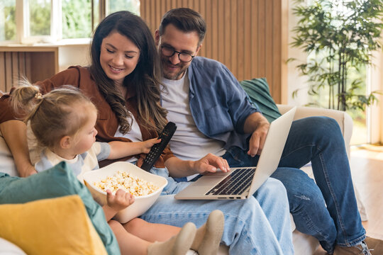 Happy young family with child enjoying new home after moving in – unpacking boxes, relaxing in living room, spending time together in kitchen, celebrating new beginning. Man, woman and daughter.
