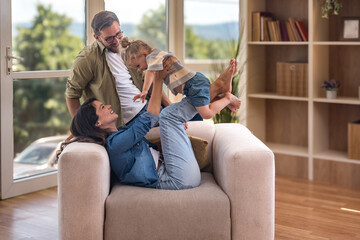 Happy young family with child enjoying new home after moving in – unpacking boxes, relaxing in...