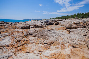  A wide-angle view of a rugged, textured rocky coastline stretching into the foreground, leading to...