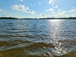 Sun reflecting on lake water surface with wind turbines in background