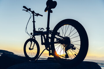A folding bike on sunrise seaside rock