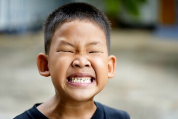 Smiling face of Asian boy. Close-up of happy childhood outdoors.