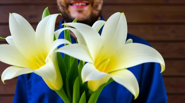 Man in love with a bouquet of white flowers of Zantedeschia aethiopica, commonly known as calla lily and arum lily. Young white caucasian man with short hair, little beard and dark eyes.
