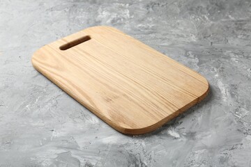 One wooden serving board on light grey textured table, closeup. Space for text