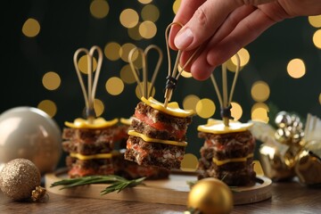 Tasty canapes with cheese on wooden table against blurred lights, closeup. Bokeh effect
