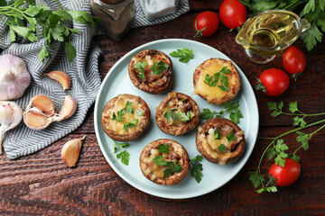 Tasty stuffed mushrooms and ingredients on wooden table, flat lay