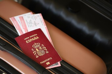 Spanish passport with tickets lies on touristic suitcase close up in airport waiting hall