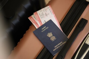 Indian passport with tickets lies on touristic suitcase close up in airport waiting hall