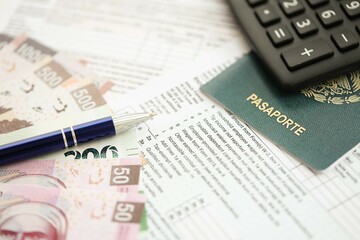 Mexican pesos money bills in big amount lies on table with pen, calculator, passport and tax forms