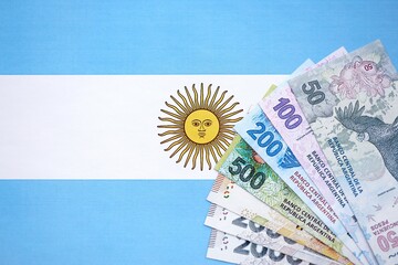 Argentine pesos money bills in big amount lies on Argentina flag close up