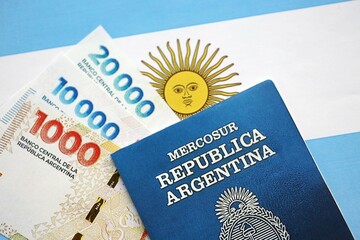 Argentine pesos money bills in big amount and passport lies on Argentina flag close up