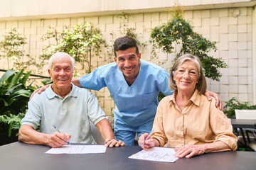 Senior patients and caregiver solving puzzles in rehabilitation facility garden