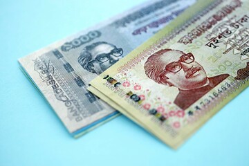 Bangladeshi taka money bills in big amount lies on teal color table close up