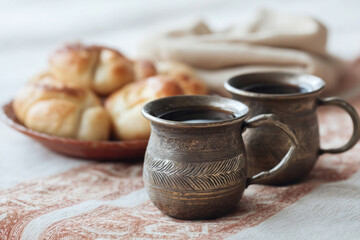Ancient charm of ornate metal cups with steaming black coffee, evoking Slavic afternoon tea rituals and Lughnasadh harvest reflections