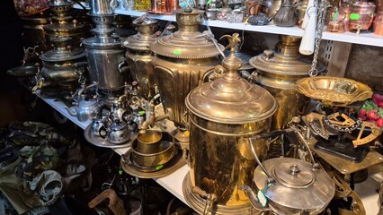 Gleaming brass samovars, teapots, and other vintage metalware displayed on shelves in an antique store, creating a nostalgic atmosphere