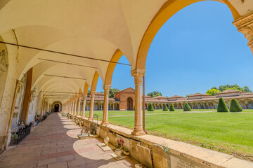 Ferrara, Italy - May 17, 2025: Experience the stunning architectural beauty of the Charterhouse of Ferrara, Italy, showcasing its elegant arches and serene garden views under a bright blue sky