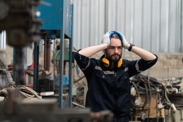 Industry factory, male worker, workshop. Male worker tired from working, looking streesed, feeling sice or unwell in place of work at factory