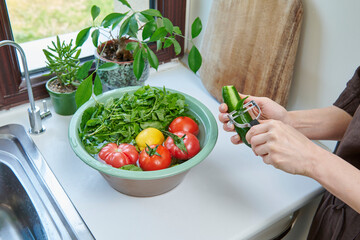 A woman washes fresh lemons, tomatoes, and leafy greens in a kitchen sink, preparing healthy ingredients near a sunlit window.