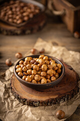 Shelled hazelnuts in a bowl placed on a wooden board