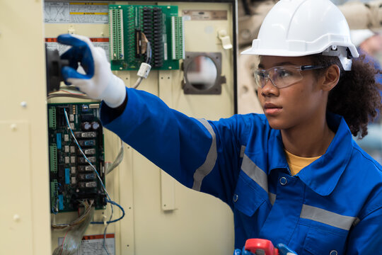 Electrician woman, Electric system on circuit board, Ampere meter. Female electrician worker checking operation electric system on circuit board in factory. Electric engineer using ampere meter tool