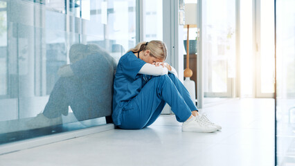 Healthcare, nurse and stress on floor in hospital hallway with bad news, treatment fail and regret. Health expert, woman and overwhelmed with anxiety for medical doubt, clinic crisis and patient loss