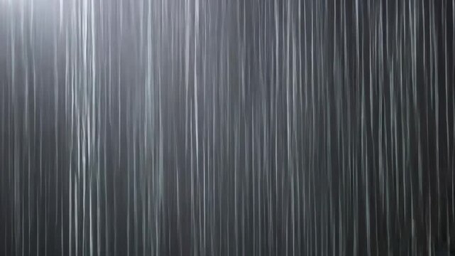 Heavy rain falling in vertical streaks on dark background with bright light from top left corner