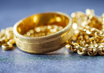Gold price, gold jewelry, close-up of gold ring and gold necklace on grey background.