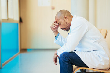 Overworked doctor suffering from stress and burnout in hospital corridor